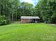 View of home from an expansive green backyard with a wooded perimeter and screened-in porch at 7316 Truelight Church Rd, Mint Hill, NC 28227