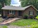 Charming brick home featuring a manicured front yard, walkway, and cozy outdoor seating area at 7316 Truelight Church Rd, Mint Hill, NC 28227