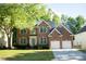 Traditional two-story brick home featuring an attached two-car garage and well-maintained landscaping at 7708 Harrington Woods Rd, Charlotte, NC 28269