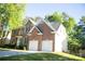 View of two-story brick home with a two-car garage and trimmed lawn at 7708 Harrington Woods Rd, Charlotte, NC 28269