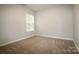 Neutral bedroom offers a bright window for natural light and plush carpet at 7830 Shiny Meadow Ln, Charlotte, NC 28215