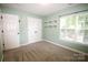 Inviting bedroom showcasing neutral walls, a window for natural light, closet, and two charming floating shelves at 7830 Shiny Meadow Ln, Charlotte, NC 28215