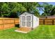A grey and white storage shed on a well-maintained lawn, surrounded by a wood privacy fence at 7921 Willhill Rd, Mint Hill, NC 28227