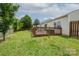Large backyard with deck, green grass, and mature trees offering privacy and a serene outdoor setting at 9623 Duxford Ln, Charlotte, NC 28269