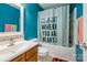 Bright bathroom featuring bold blue walls, a tiled sink, and a shower-tub combo with a statement shower curtain at 9623 Duxford Ln, Charlotte, NC 28269