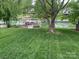 Scenic backyard view featuring lush green lawn, mature trees, and a waterfront area with docks and boats at 132 Marina Ln, Mooresville, NC 28117
