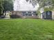 Spacious backyard with lush green grass, a wooden deck, shed, and a charming two-story home in the background at 132 Marina Ln, Mooresville, NC 28117