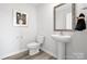 Modern half bathroom featuring a white pedestal sink and toilet, complemented by wood-look flooring at 3064 Ora Smith Rd, Lincolnton, NC 28092