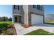 A close up of the exterior featuring stone accents and gray siding plus a large two car garage at 3064 Ora Smith Rd, Lincolnton, NC 28092