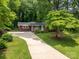 A single-story home surrounded by mature trees, a well-maintained lawn, and a long concrete driveway at 3120 7Th Street Ne Dr, Hickory, NC 28601