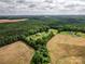 Drone shot of property featuring a pond, home and outbuildings surrounded by farmland and woods at 4115 Jenkins Rd, Marshville, NC 28103