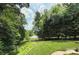Expansive backyard with lush landscaping, a serene lake view and mature trees at 4323 Rosecliff Dr, Charlotte, NC 28277