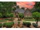 Beautiful brick home featuring a well-manicured lawn and a picturesque landscape, with a cloudy orange and pink sky at 4323 Rosecliff Dr, Charlotte, NC 28277