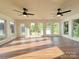 Bright sunroom or living room featuring hardwood floors, many windows, and modern ceiling fans at 5323 Flat Creek Rd, Heath Springs, SC 29058