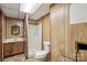 A well-lit bathroom featuring wood paneling, a sink, a toilet, and a shower at 5626 Sandhurst Rd, Hickory, NC 28602