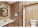 A well-lit bathroom featuring wood paneling, a sink, a toilet, and a shower at 5626 Sandhurst Rd, Hickory, NC 28602