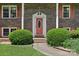 Close up of the brick home's front door, flanked by vibrant green bushes at 5626 Sandhurst Rd, Hickory, NC 28602