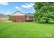 A lush backyard featuring mature trees, a small deck, and a classic brick exterior at 7189 Bovine Ln # 28, Harrisburg, NC 28075