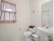 This powder room features a pedestal sink, toilet, and decorative window treatment at 7189 Bovine Ln # 28, Harrisburg, NC 28075