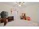 Neutral bedroom with a ceiling fan, window, desk, chair and shelving unit at 7189 Bovine Ln # 28, Harrisburg, NC 28075