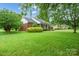 Brick home featuring a lush green lawn, complemented by mature trees for privacy and shade at 7189 Bovine Ln # 28, Harrisburg, NC 28075