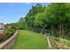 Backyard with wrought iron fence, stone wall, lush landscaping, and green grass at 7339 Millstone Sw Cir, Concord, NC 28025