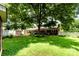 Spacious backyard featuring a large tree, green grass, flower beds, and a white picket fence at 839 Montford Dr, Charlotte, NC 28209