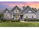 Charming home featuring stone accents, a well-manicured lawn, and a welcoming front porch with rocking chairs at 8709 Raven Top Dr, Mint Hill, NC 28227