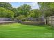 This home features a large well-maintained lawn and a stone block retaining wall with a wood fence at 933 Old Charlotte Rd, Concord, NC 28027