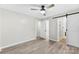 Bright main bedroom featuring a ceiling fan, light gray walls, wood floors, and an ensuite bathroom with shower at 103A N Tracy St, Kings Mountain, NC 28086