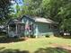 Charming blue home with red shutters and a welcoming front porch surrounded by lush green trees and lawn at 1051 S Brady Ave, Newton, NC 28658