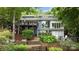 Two story exterior showcasing a deck, large windows, a stone patio, and lush landscaping, enhancing outdoor living at 1111 Palmyra Dr, Fort Mill, SC 29708