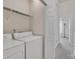 A laundry room with a white washer and dryer set, complemented by shelving and access to a hallway at 11218 Grass Field Rd # 1083, Charlotte, NC 28213
