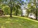 Expansive backyard with lush lawn and mature trees leading to lake frontage and dock access at 1433 Kern Carlton Rd, Salisbury, NC 28146