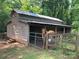 A horse standing in front of a barn with a fence in the yard surrounded by lush green trees at 1433 Kern Carlton Rd, Salisbury, NC 28146
