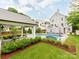 A lush backyard features an in-ground pool and spa, patio with an outdoor kitchen, a seating area, and pristine landscaping at 1600 Princeton Ave, Charlotte, NC 28209