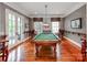 Spacious game room boasts a classic billiard table, hardwood floors, and abundant natural light from the french doors at 1600 Princeton Ave, Charlotte, NC 28209