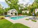 Outdoor space featuring an in-ground pool, spa, pool house, patio with lounge chairs, and lush landscaping at 1600 Princeton Ave, Charlotte, NC 28209