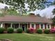 Inviting red brick house with a well-maintained lawn, manicured shrubs, and colorful flowering bushes at 1614 Statesville Blvd, Salisbury, NC 28144