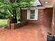 Red brick patio with a brick planter, and a glimpse of the lush surrounding greenery at 1614 Statesville Blvd, Salisbury, NC 28144