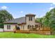 Backyard view of the home's deck with grill and furniture, siding, roof, and mature trees around the property at 1730 Eden Glen Dr, Dallas, NC 28034