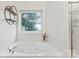 A luxurious jetted bathtub sits beneath a window with decorative glass providing natural light and privacy at 1730 Eden Glen Dr, Dallas, NC 28034