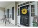 Welcoming front door with a wreath, black hardware, and a charming porch setting with a 'Welcome to our home' sign at 1730 Eden Glen Dr, Dallas, NC 28034