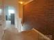 Hallway featuring a brick accent wall with modern glass railing and carpeted floors leading to other rooms at 2411 Bonterra Blvd, Indian Trail, NC 28079