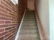 View of the carpeted staircase with brick accent wall leading to the next level of the house at 2411 Bonterra Blvd, Indian Trail, NC 28079