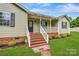 Inviting front porch with wooden stairs and white railing, set against brick foundation at 3125 Leonard Dr, Gastonia, NC 28056