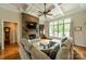 A cozy living room features a stone fireplace, ceiling fan, and large windows at 3500 Maple Wood Dr, Denver, NC 28037