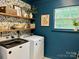 Bright laundry room features modern washer and dryer, blue walls, and lemon print wallpaper with decorative shelving at 4113 Edgeview Dr, Indian Trail, NC 28079
