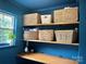 Bright laundry room featuring built-in shelves, stylish storage baskets and blue accent wall at 4113 Edgeview Dr, Indian Trail, NC 28079