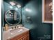 Stylish powder room with a dark teal accent wall, decorative mirror, and marble countertop at 4113 Edgeview Dr, Indian Trail, NC 28079